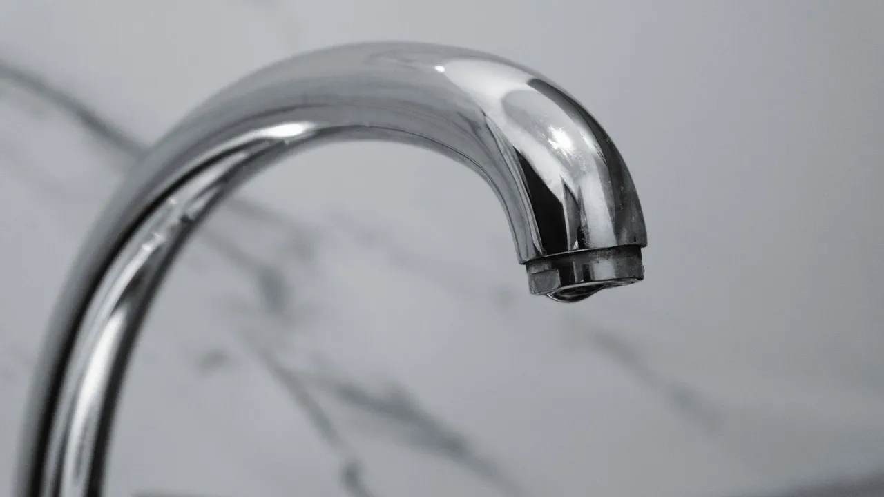 Hands repairing a leaky kitchen faucet with a wrench