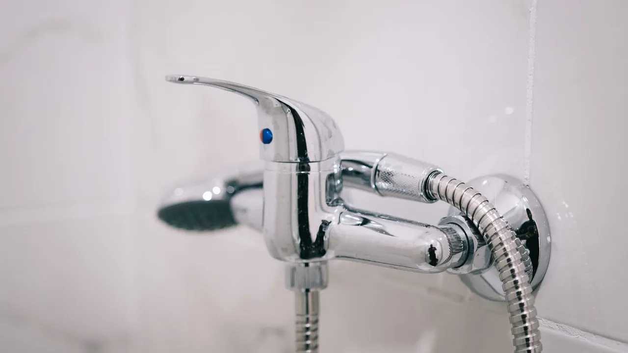Plumber flushing a residential tank water heater with a hose
