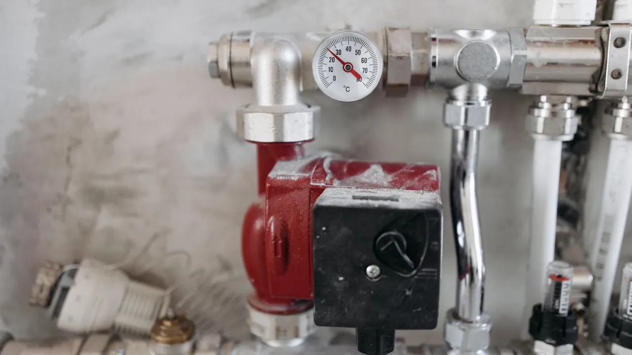 Plumber testing water pressure at an outdoor faucet with a gauge